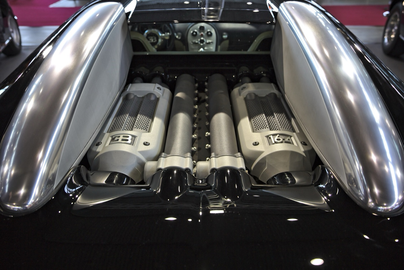 The Veyron’s W16 engine seen through the open rear deck, with two silver cam covers marked EB and 16.4 either side of twin intake ducts