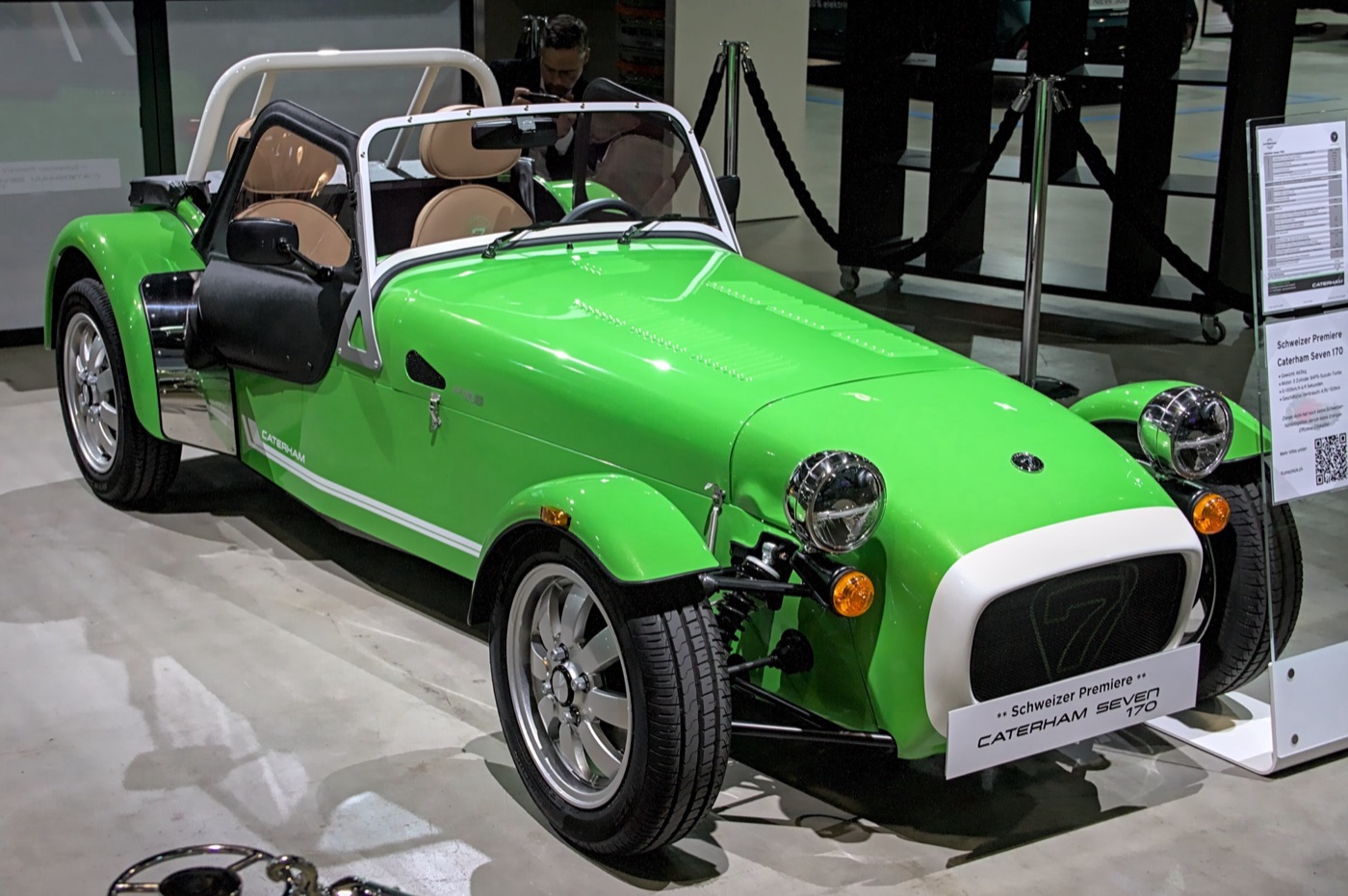 Bright green Caterham Seven 170 with a white nose surround and tan seats on a motor show stand
