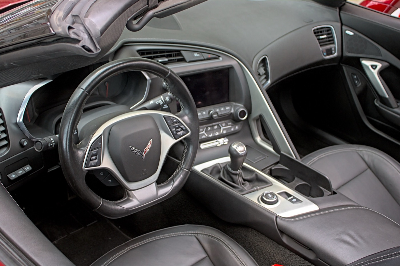 Black leather cockpit of a C7 Corvette with a manual gear lever, drive-mode dial and eight-inch touchscreen