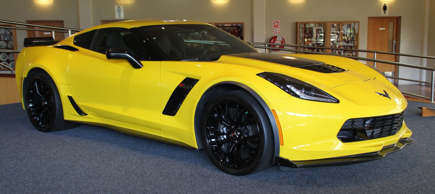 Yellow C7 Corvette Z06 coupe with black wheels, black bonnet vent and a carbon front splitter, indoors