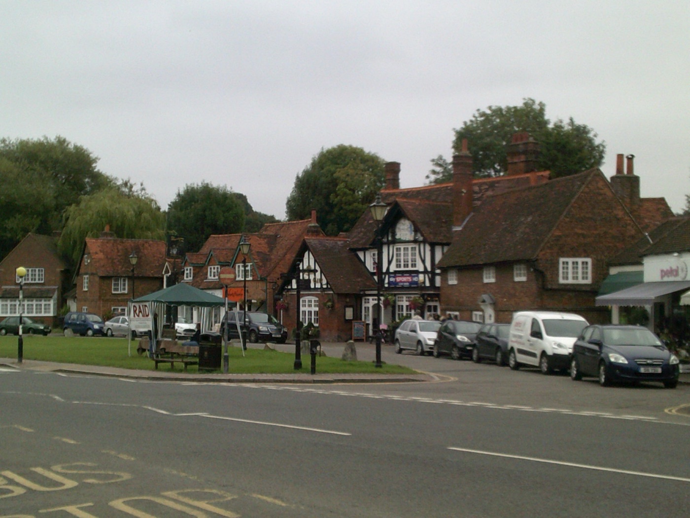 Village green at Chalfont St Giles with half-timbered and red-brick buildings and parked cars