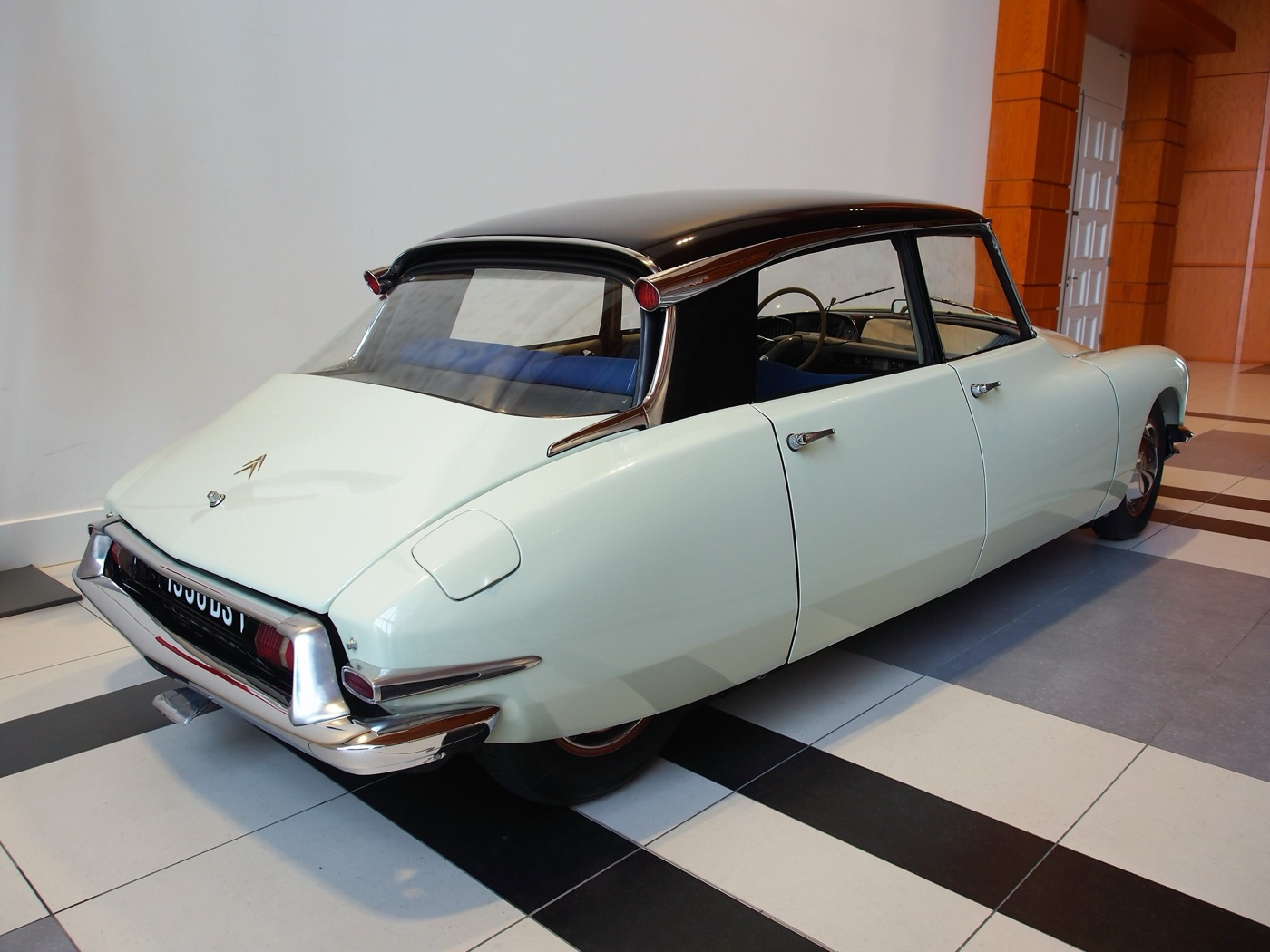 Rear three-quarter view of a pale green 1956 Citroën DS 19 with a black roof, roof-mounted indicator trumpets and covered rear wheels