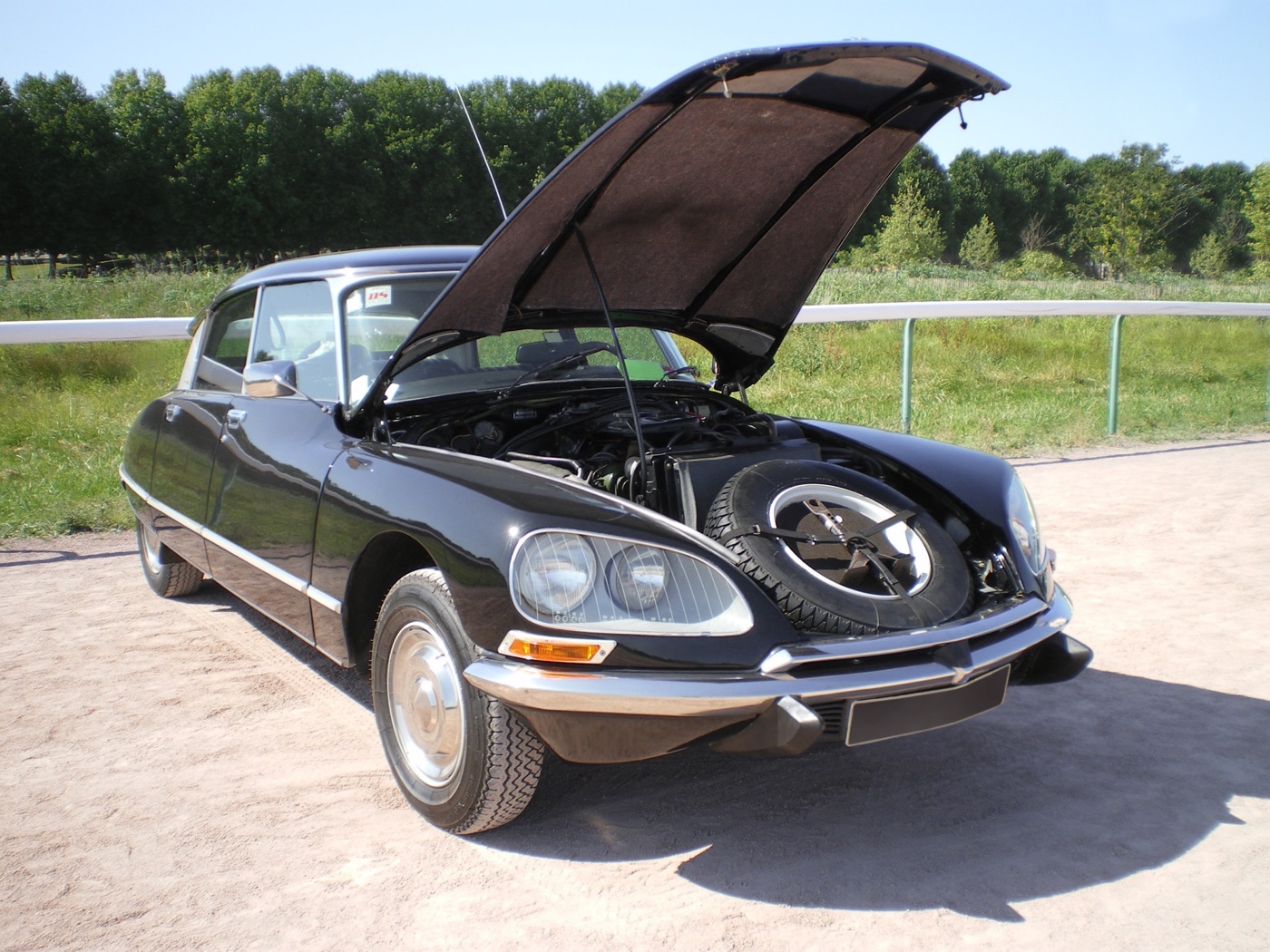 Black third-series Citroën DS saloon with its bonnet raised, showing the spare wheel stowed ahead of the engine