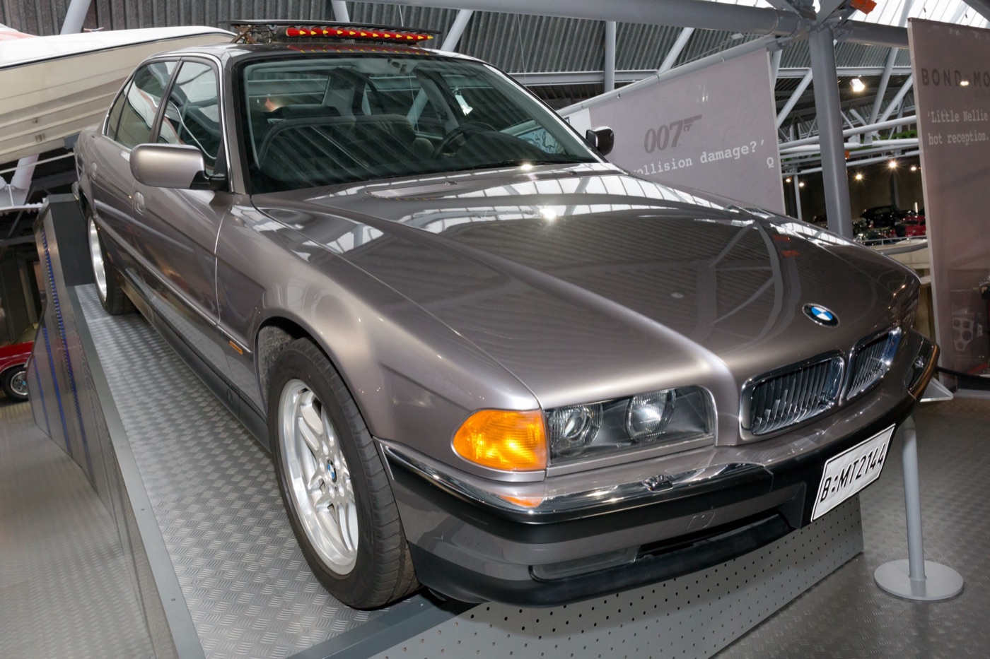 Grey BMW 750iL saloon from Tomorrow Never Dies with a row of red-tipped missiles raised from its sunroof, on display at Bond in Motion