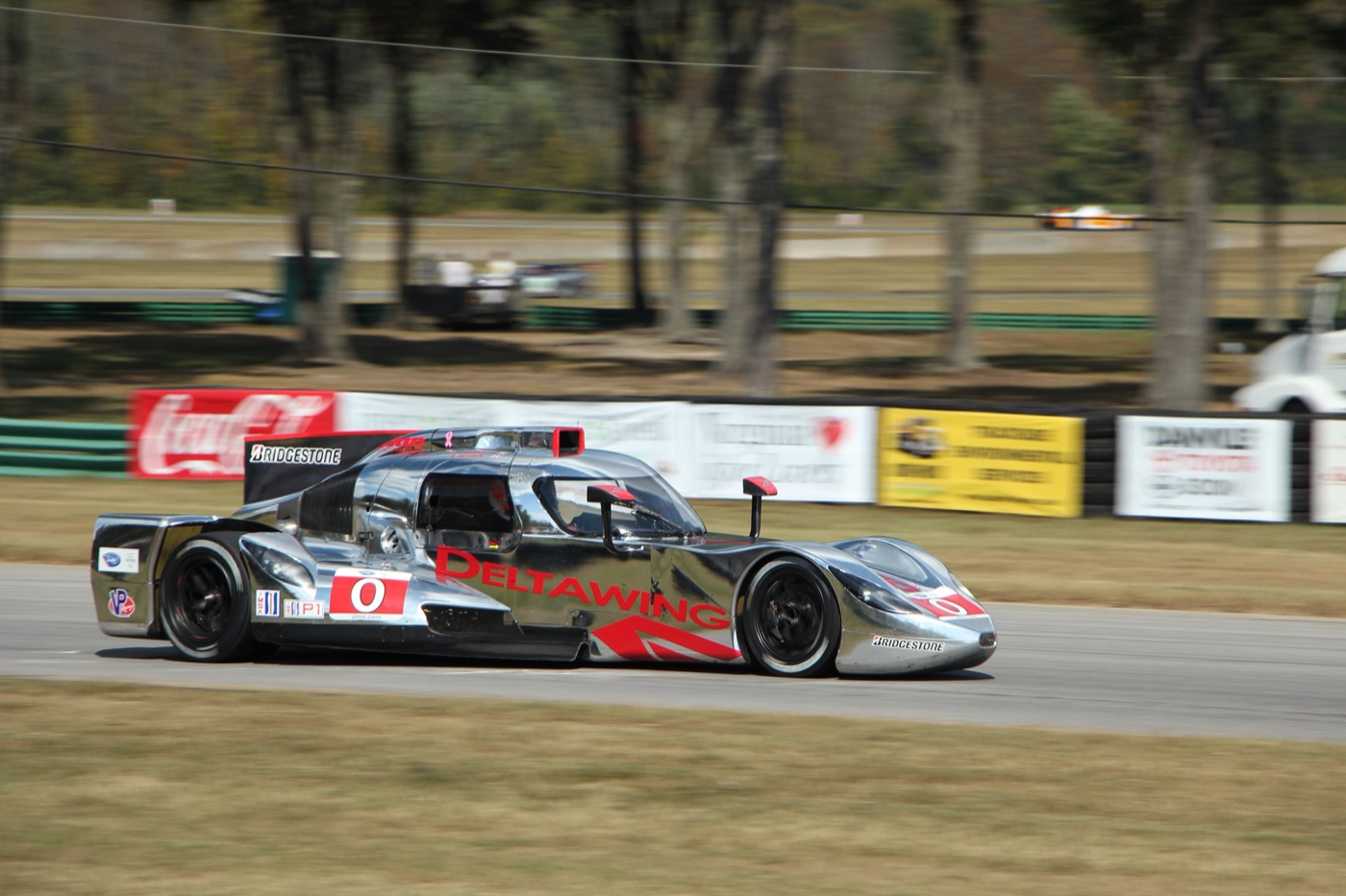 Chrome DeltaWing coupe with red lettering and a roof-mounted air scoop at speed at Virginia International Raceway