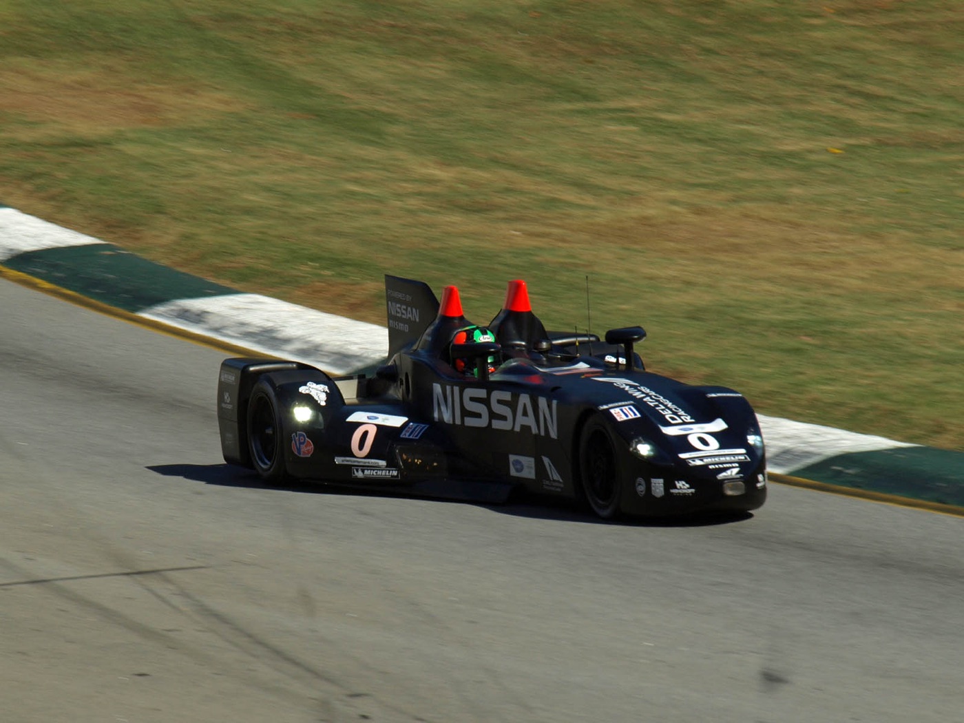 Black number 0 DeltaWing with orange-tipped roll hoops cornering at Road Atlanta