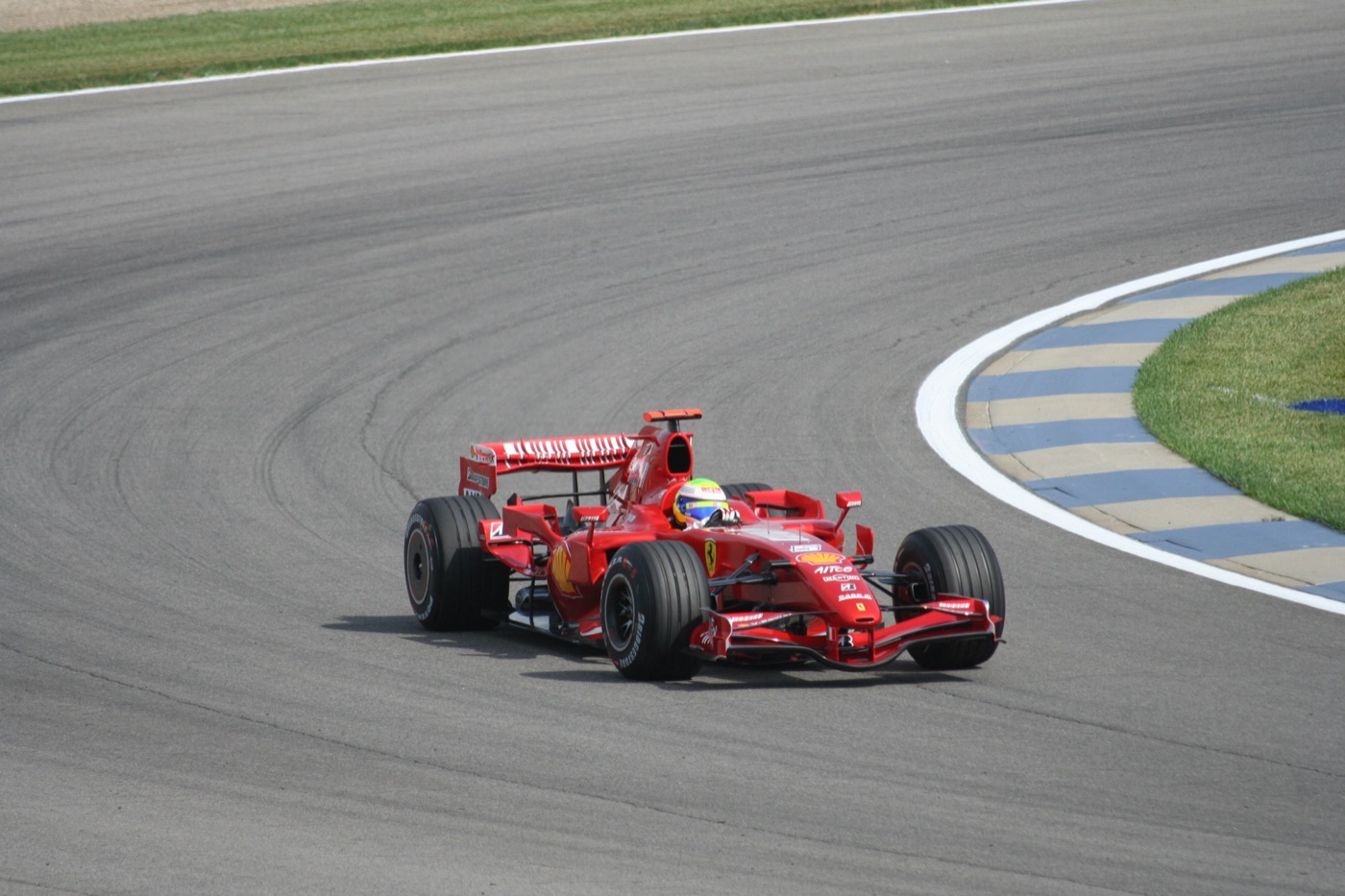 Red Ferrari F2007 Formula One car driven by Felipe Massa turning out of a corner with blue and white kerbs at Indianapolis