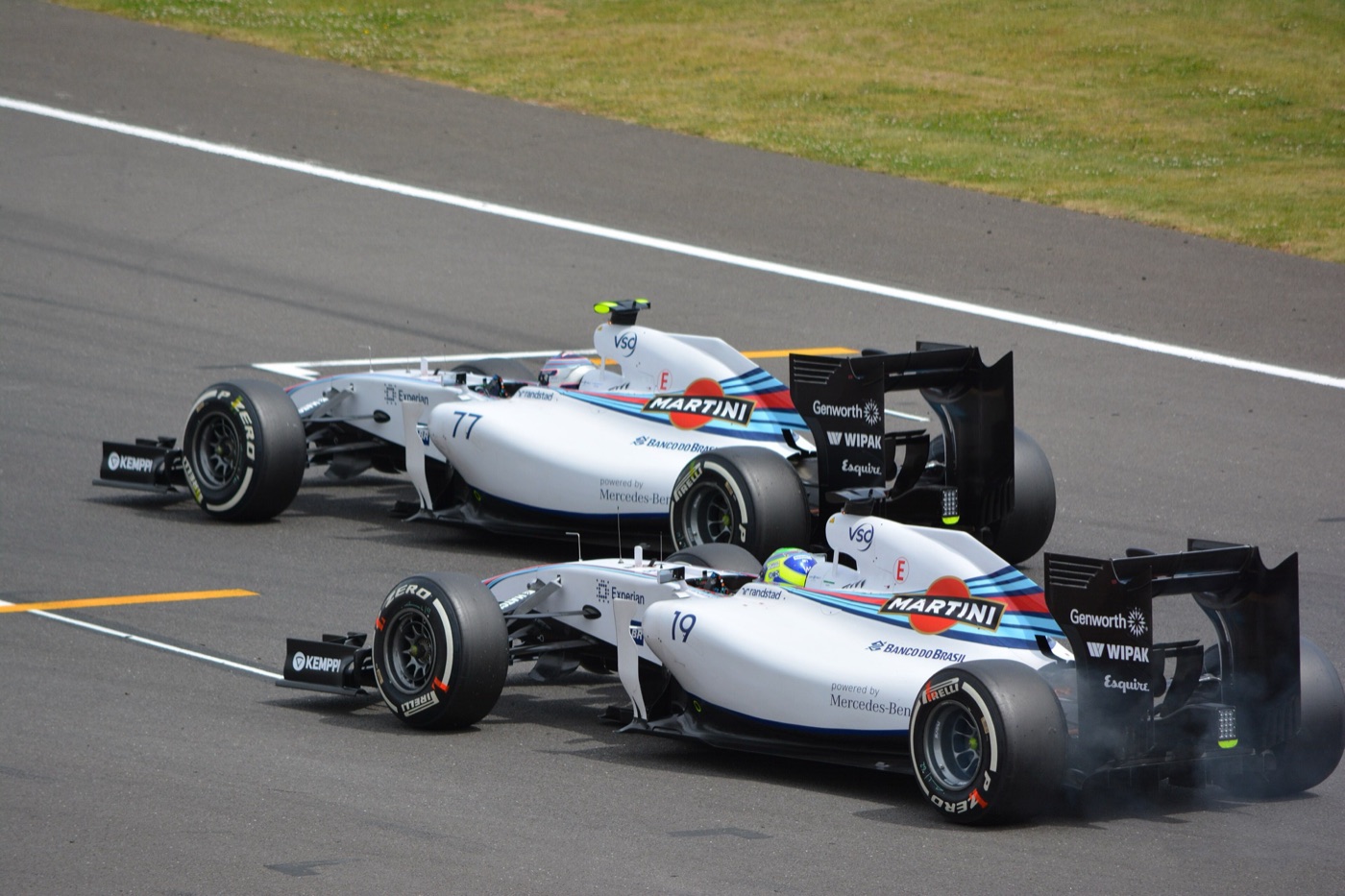 Two white Williams FW36 cars in Martini stripes, numbers 19 and 77, side by side on the track at Silverstone