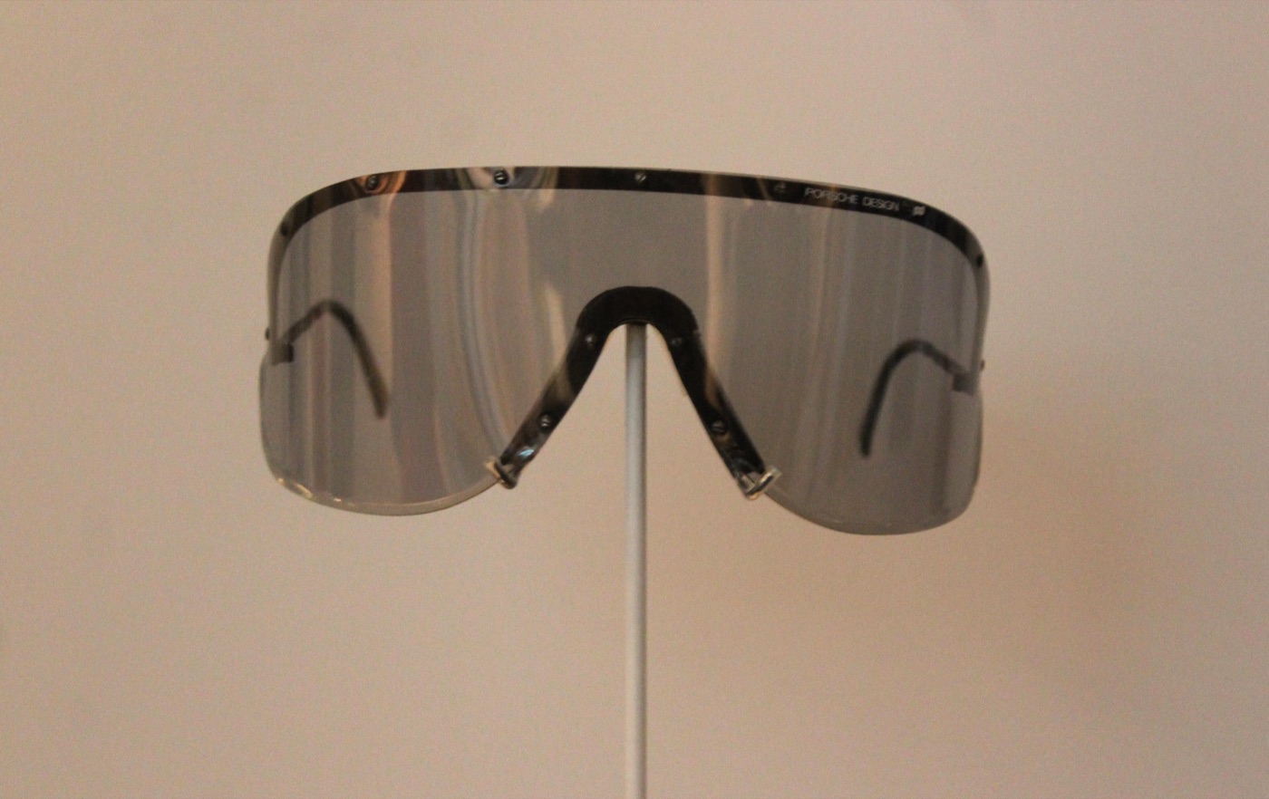 Mirrored Porsche Design shield sunglasses with a single wraparound lens, displayed on a stand