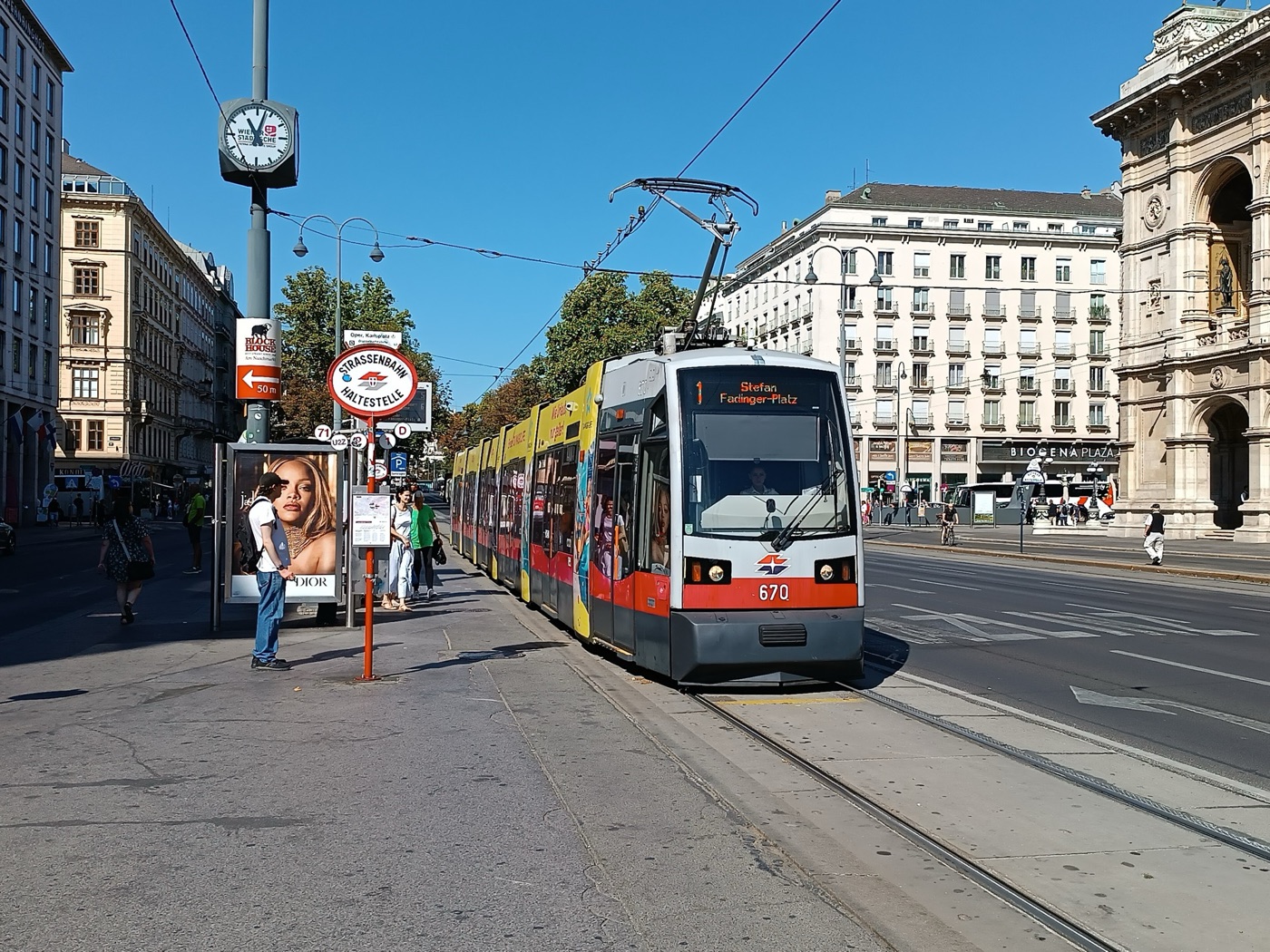 Vienna ULF low-floor tram number 670 in red, grey and advertising livery at a city-centre stop