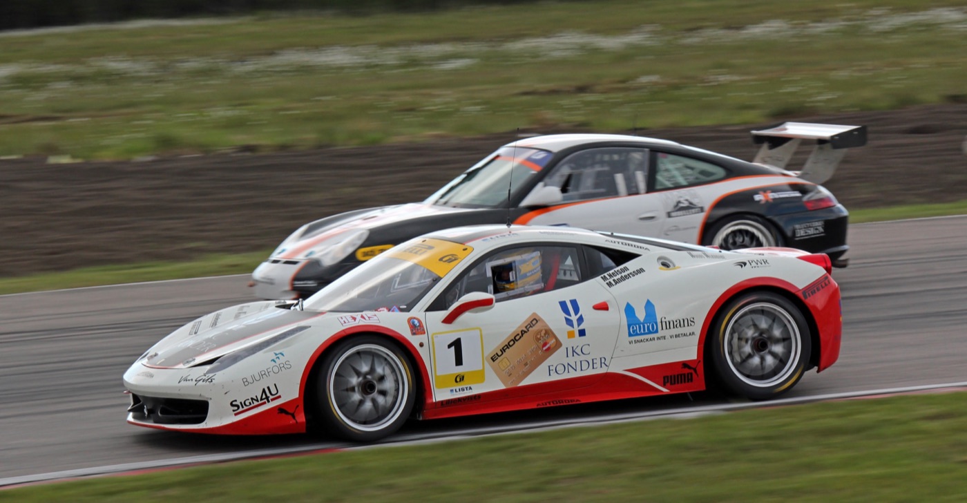 White and red Ferrari 458 Challenge race car number 1 on track beside a Porsche