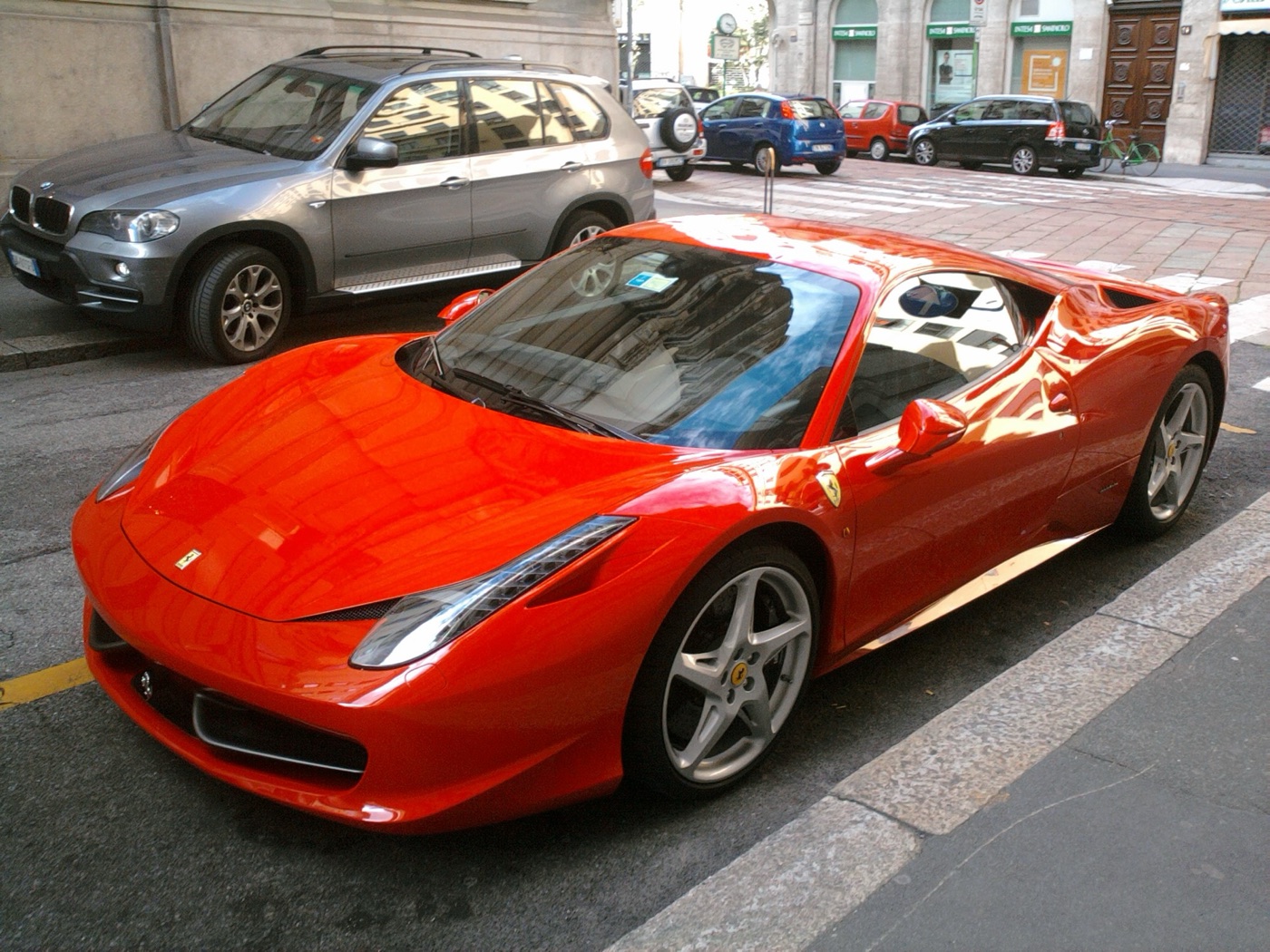 Red Ferrari 458 Italia with silver five-spoke wheels parked at the kerb in a city street