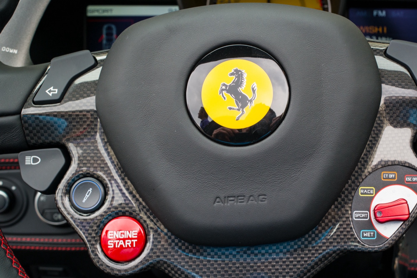 Carbon-trimmed Ferrari 458 steering wheel with a red Engine Start button and the manettino switch set to Sport