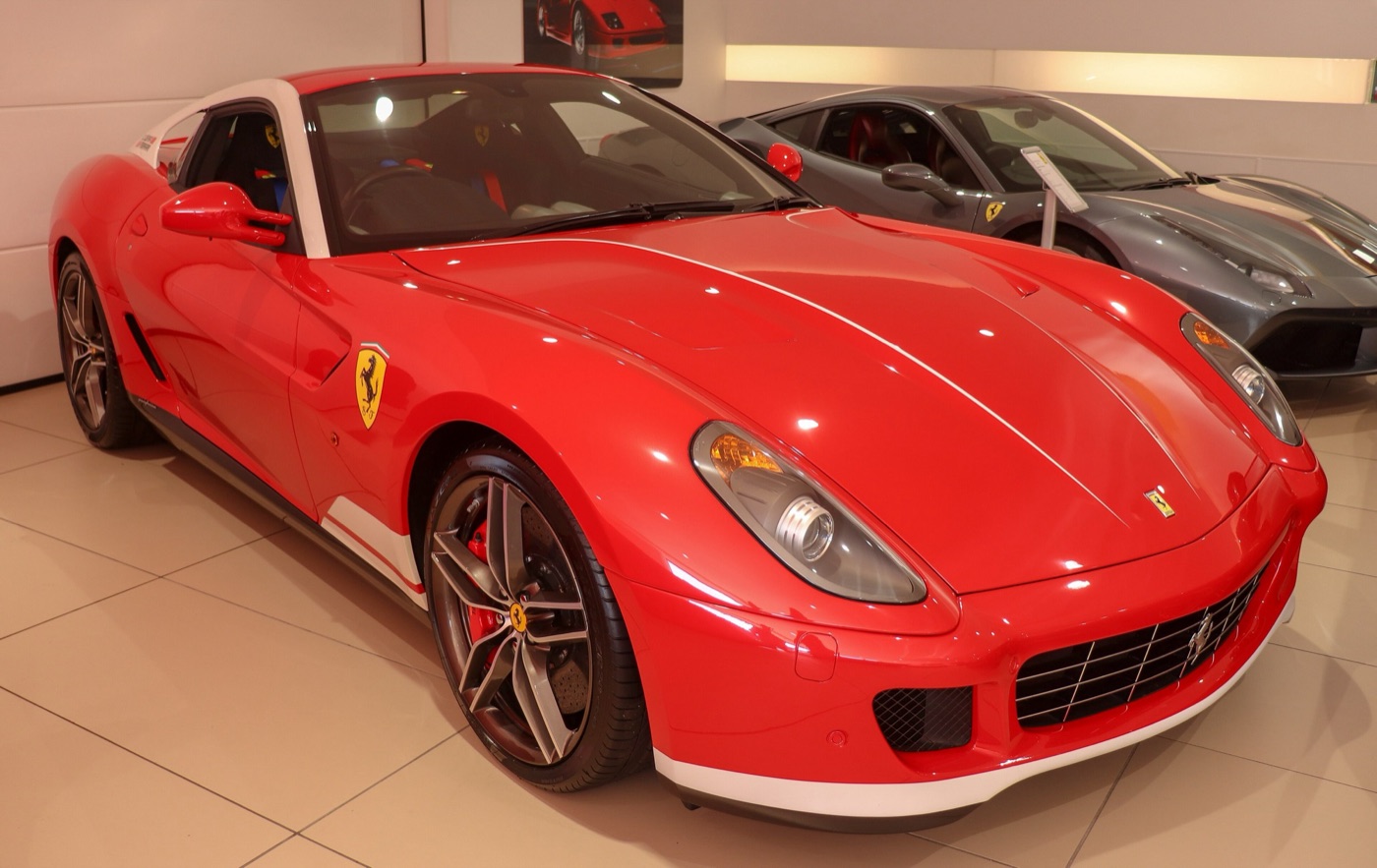 Red Ferrari 599 GTB 60F1 with white stripes on the bumper, sills and A-pillars in a showroom