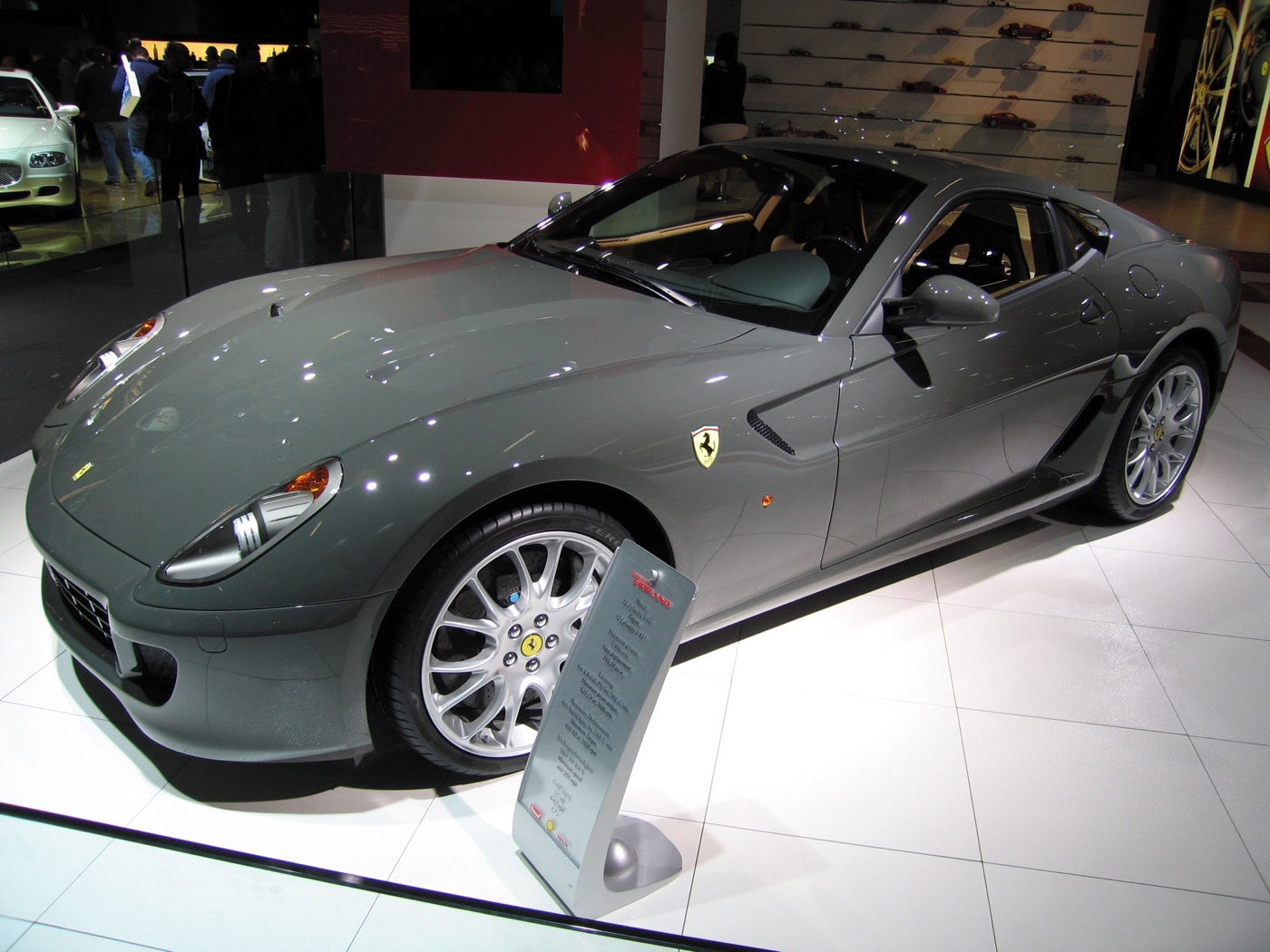 Grey Ferrari 599 GTB Fiorano on a white motor show stand with an information board