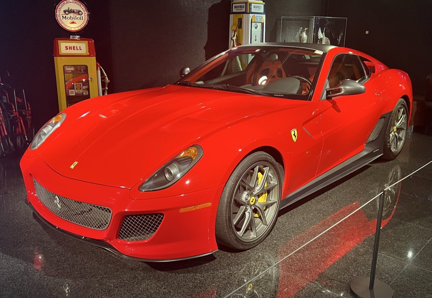 Red Ferrari 599 GTO with grey wheels and mesh grille in a museum display