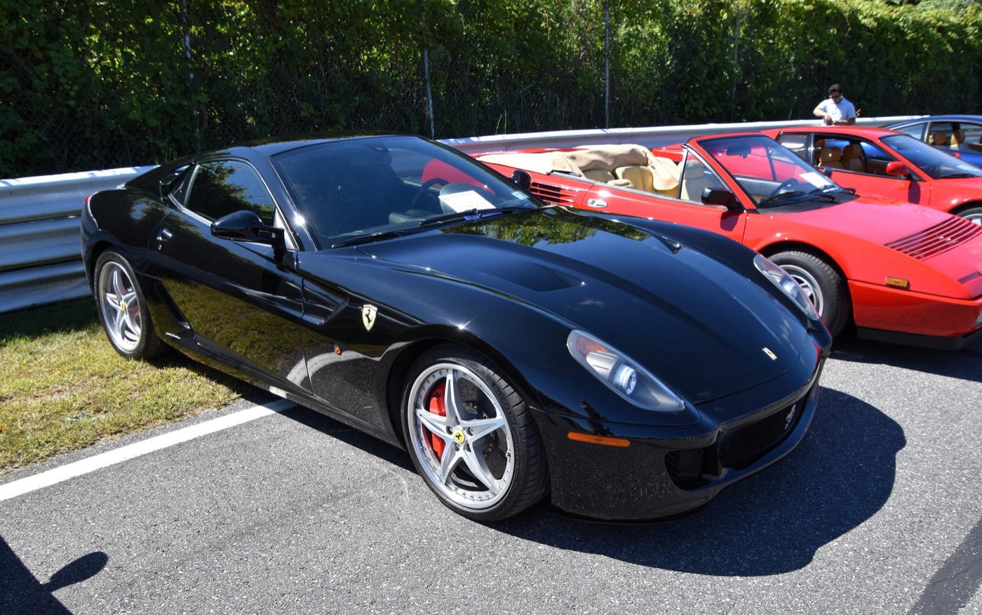 Black 2010 Ferrari 599 GTB Fiorano HGTE with silver wheels and red brake calipers at a car show