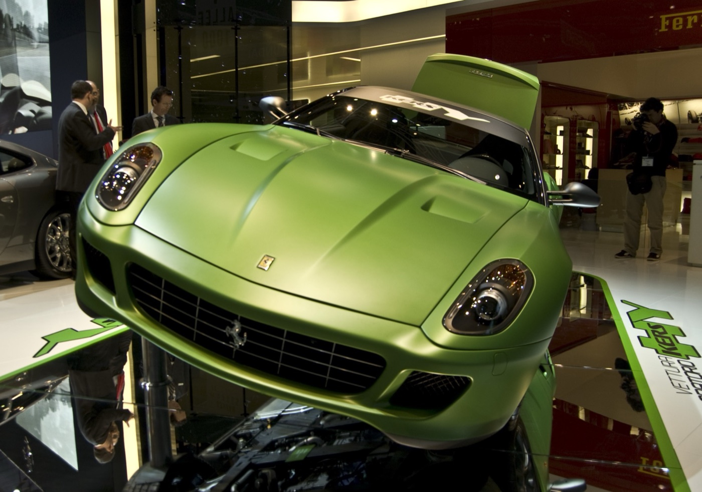 Matt green Ferrari 599 HY-KERS prototype on a raised stand at a motor show