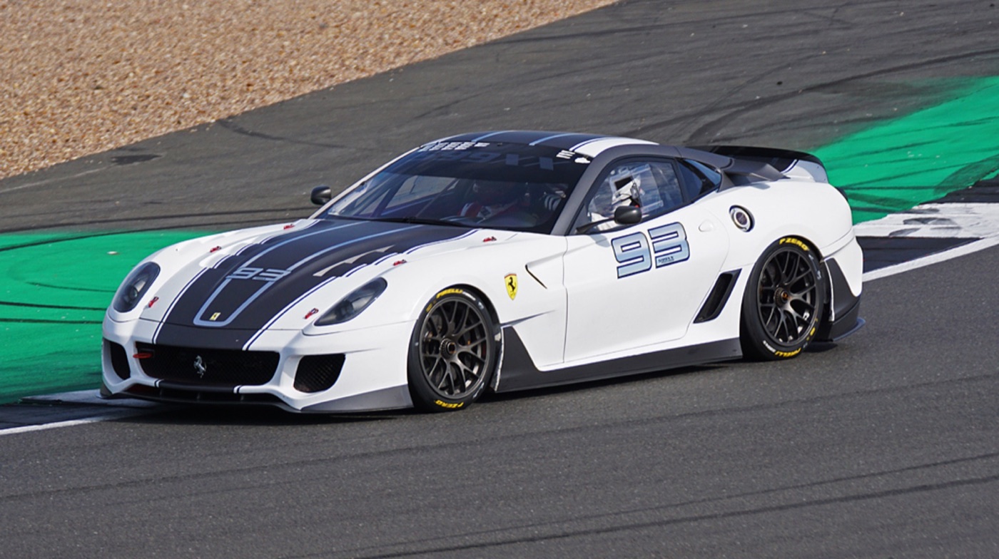 White Ferrari 599XX with a dark blue stripe and race number 93 cornering at Silverstone