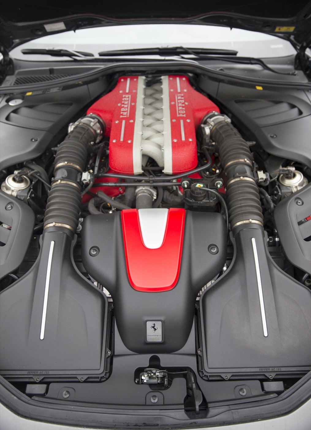 Engine bay of a Ferrari FF seen from above, with the red-topped V12 and its two intake tracts