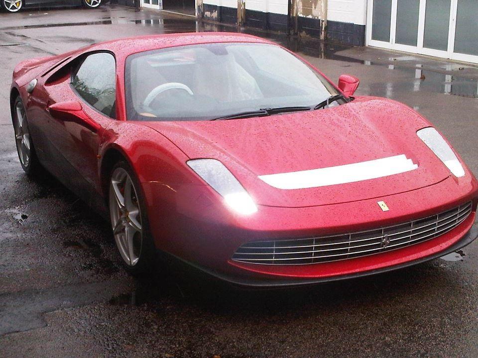 Dark red Ferrari SP12 EC with a white bonnet stripe parked on a wet forecourt