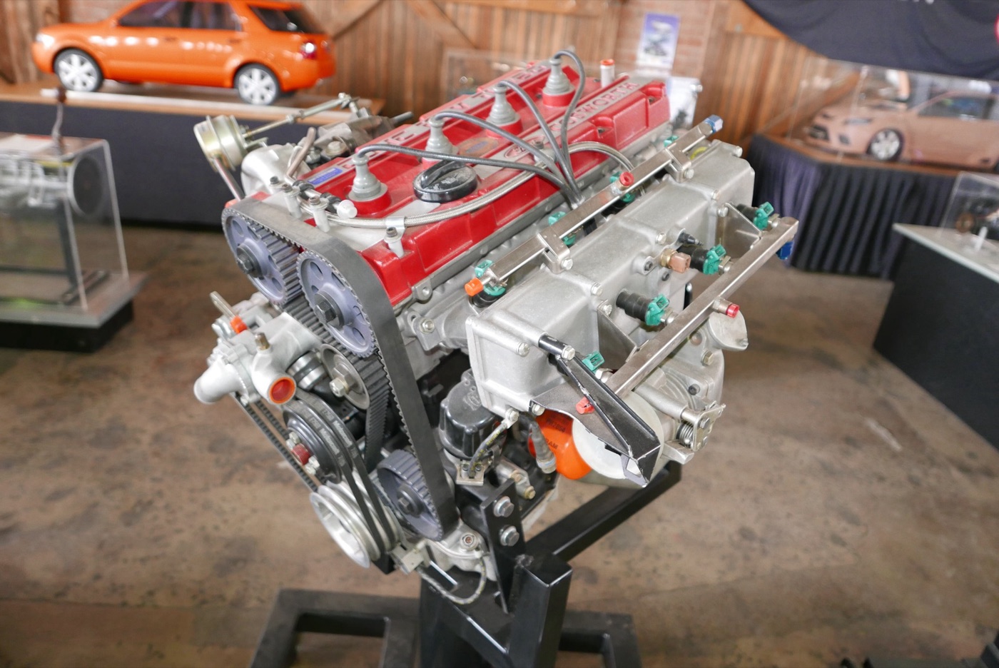 Ford Cosworth YB four-cylinder engine on a display stand, with a red cam cover, toothed cam belt and two rows of fuel injectors