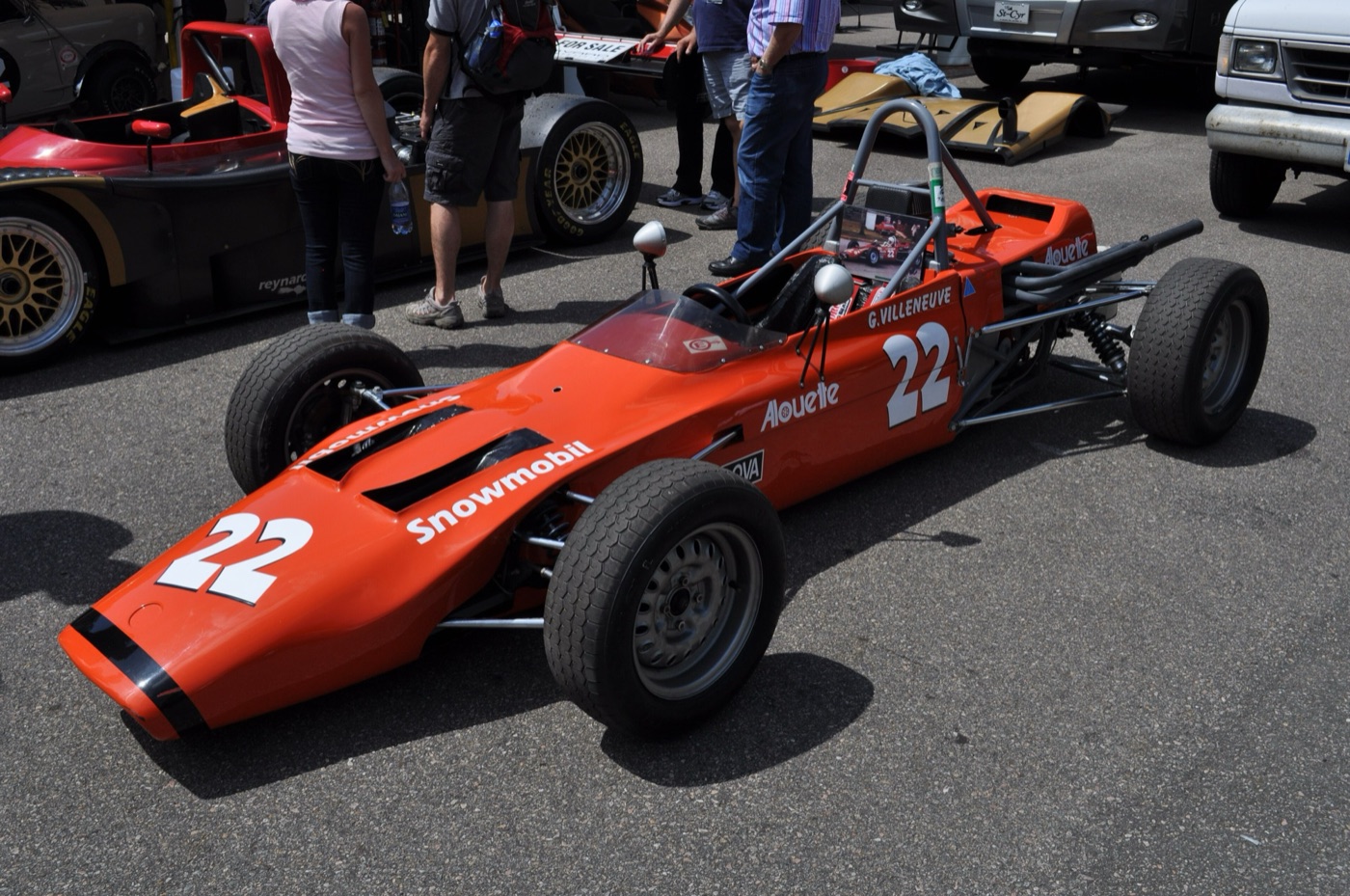 Orange Magnum MkIII Formula Ford single-seater, number 22, with G. Villeneuve and Alouette lettering on its side, parked in a paddock