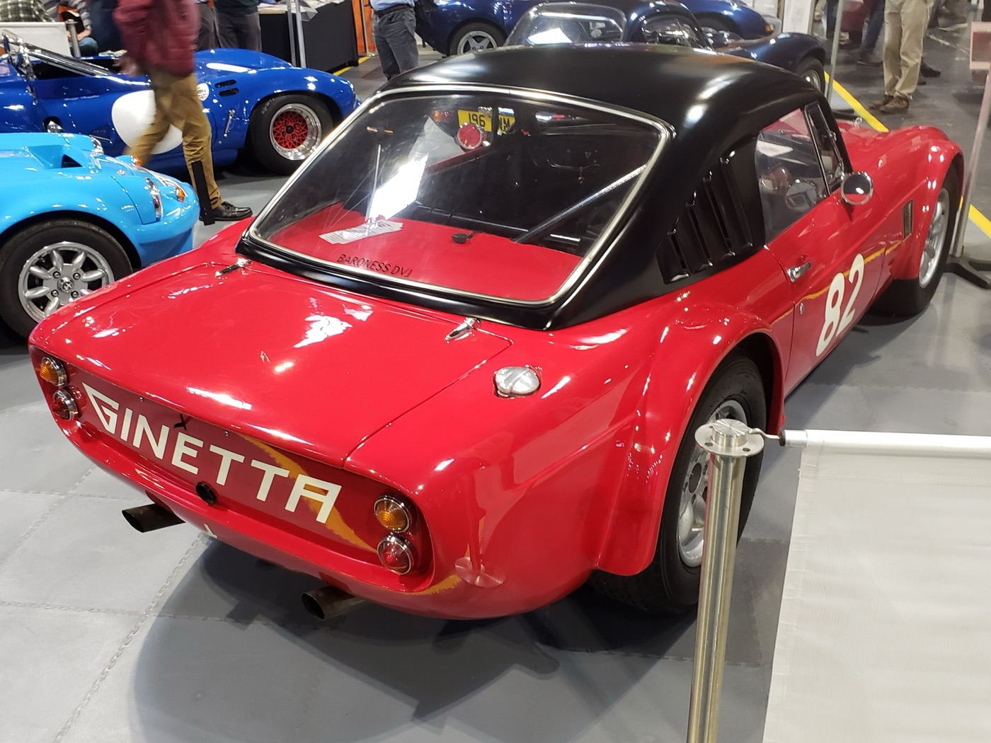 Red Ginetta G10 coupé with a black hardtop and race number 82, seen from the rear with GINETTA across the tail