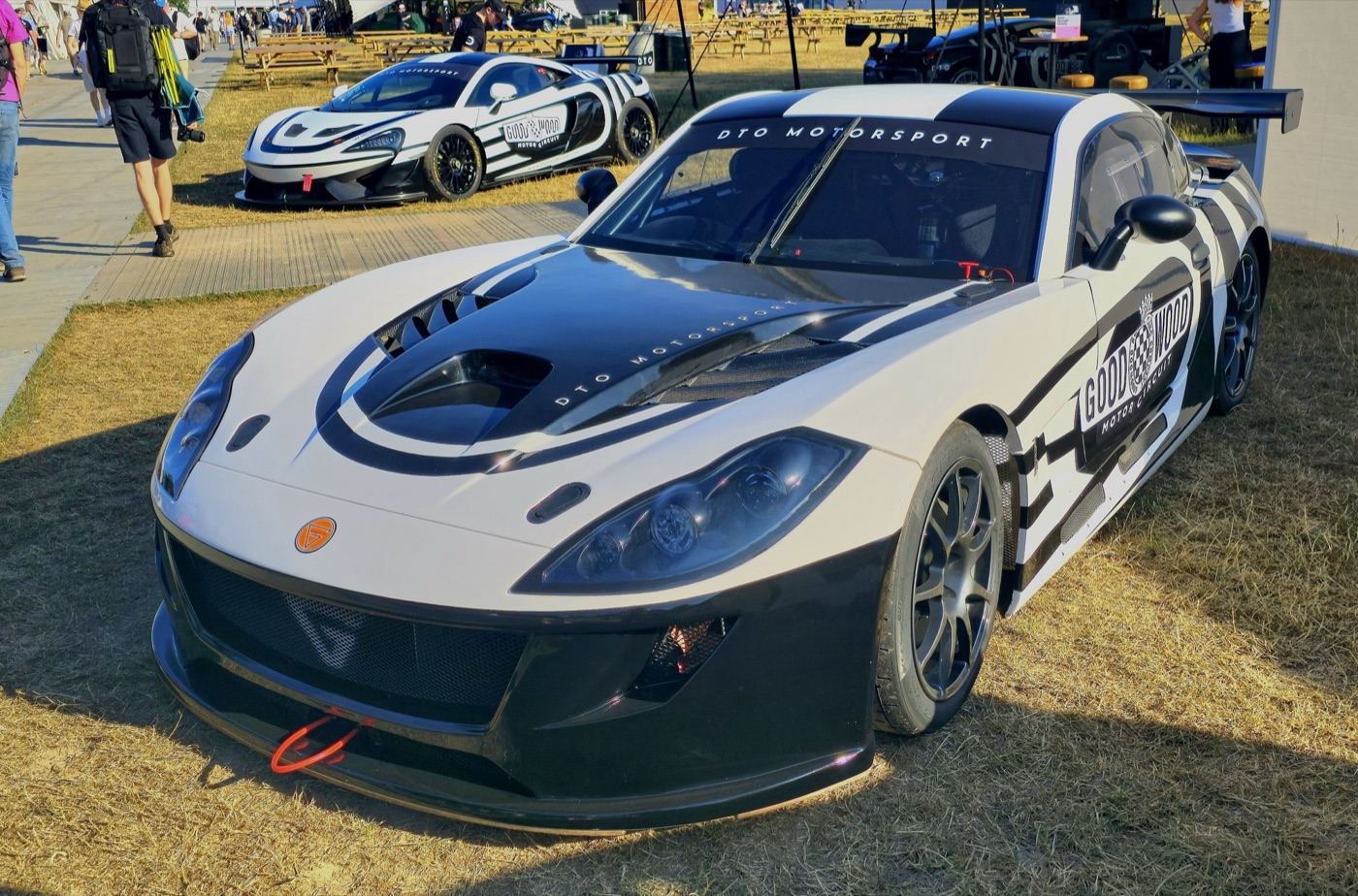 White and black Ginetta G56 race car with a large rear wing on display on grass