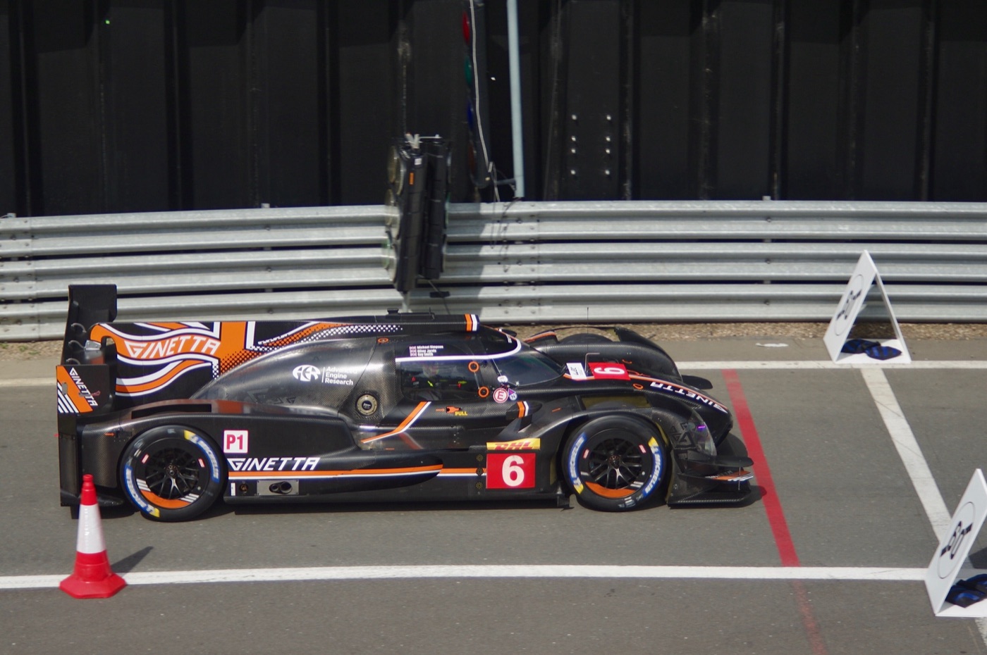 Black and orange Ginetta G60-LT-P1 prototype, number 6, in the pit lane at Silverstone