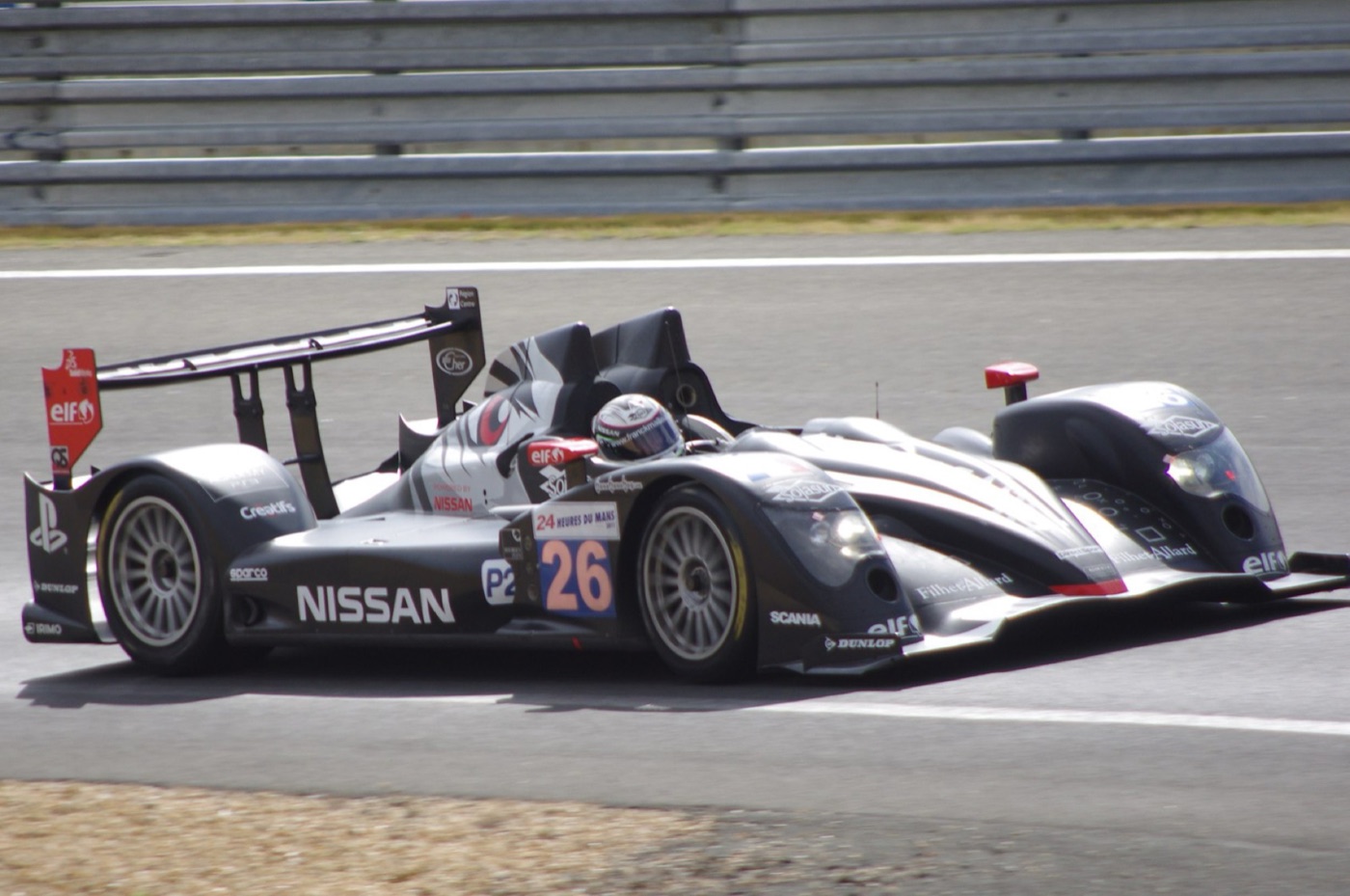 Black Signatech Oreca 03 Nissan LMP2 prototype, number 26, with a PlayStation logo on its rear fin, cornering at Le Mans