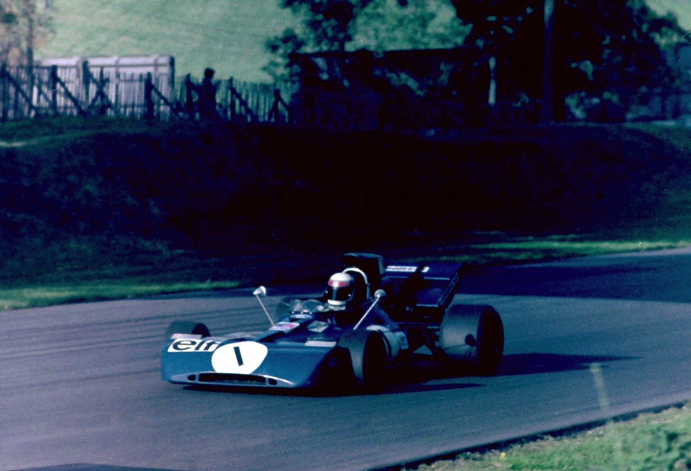 Jackie Stewart driving the dark blue Tyrrell 003, number 1, through a corner at Brands Hatch with trees behind