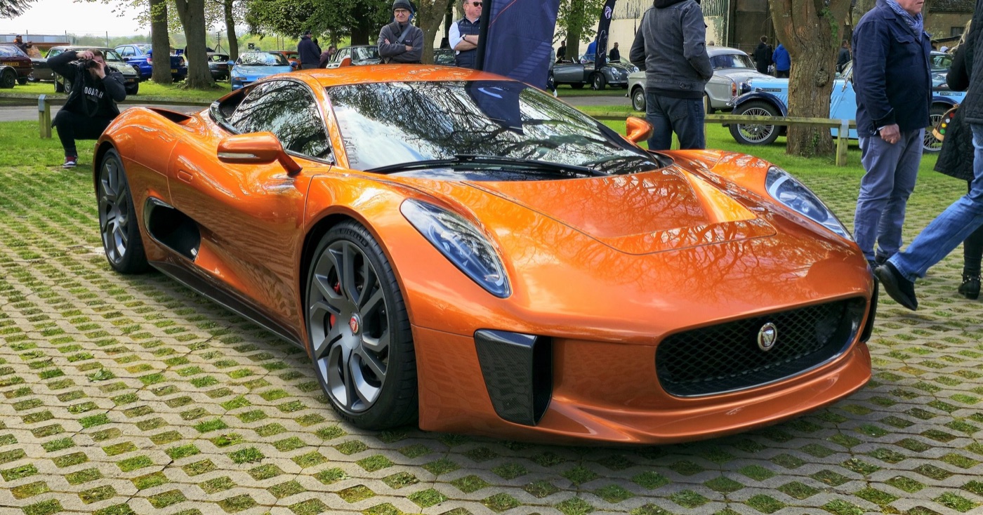 Orange Jaguar C-X75 parked on grass pavers among visitors at a car meeting