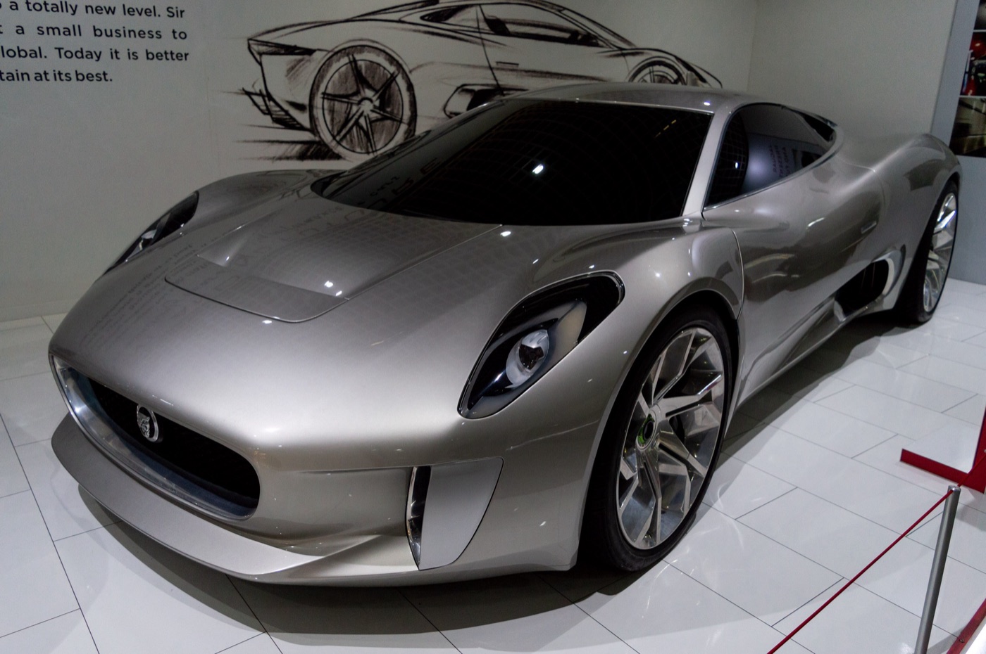 Three-quarter front view of the silver C-X75 concept in front of a wall sketch of the car