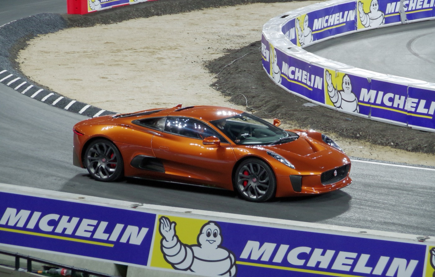 Orange Jaguar C-X75 driving on a floodlit track lined with Michelin barriers