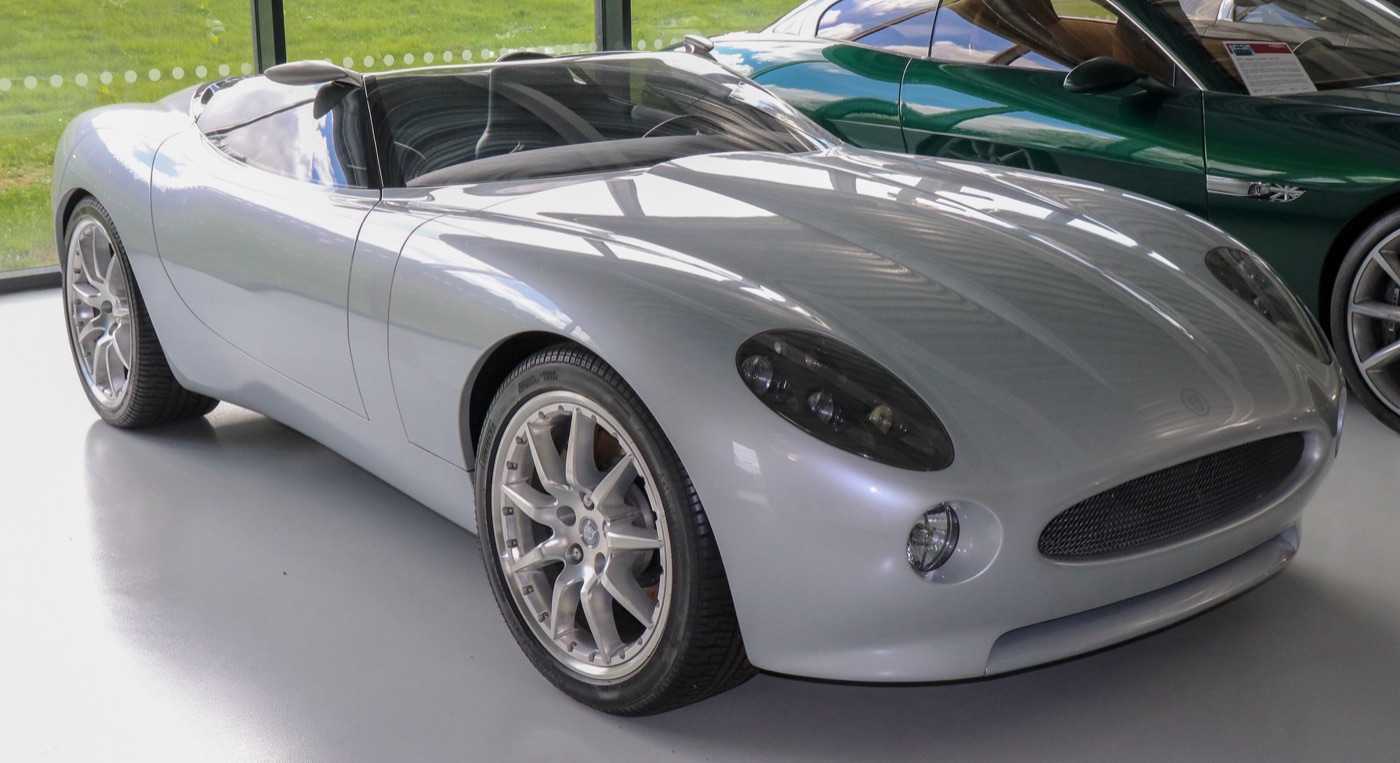 Silver Jaguar F-Type concept roadster of 2000 with oval headlamps, displayed indoors beside a green Jaguar