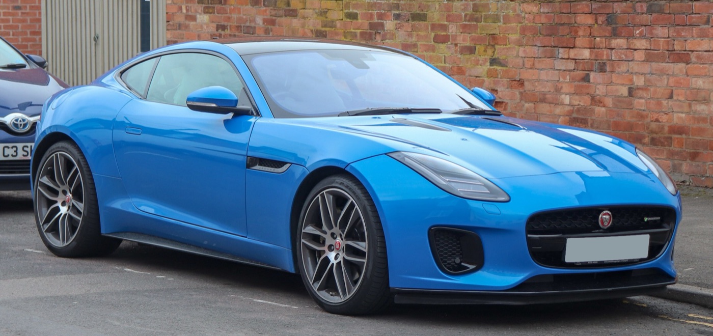 Bright blue 2017 Jaguar F-Type R-Dynamic coupe with LED headlamps and grey alloy wheels parked by a brick wall