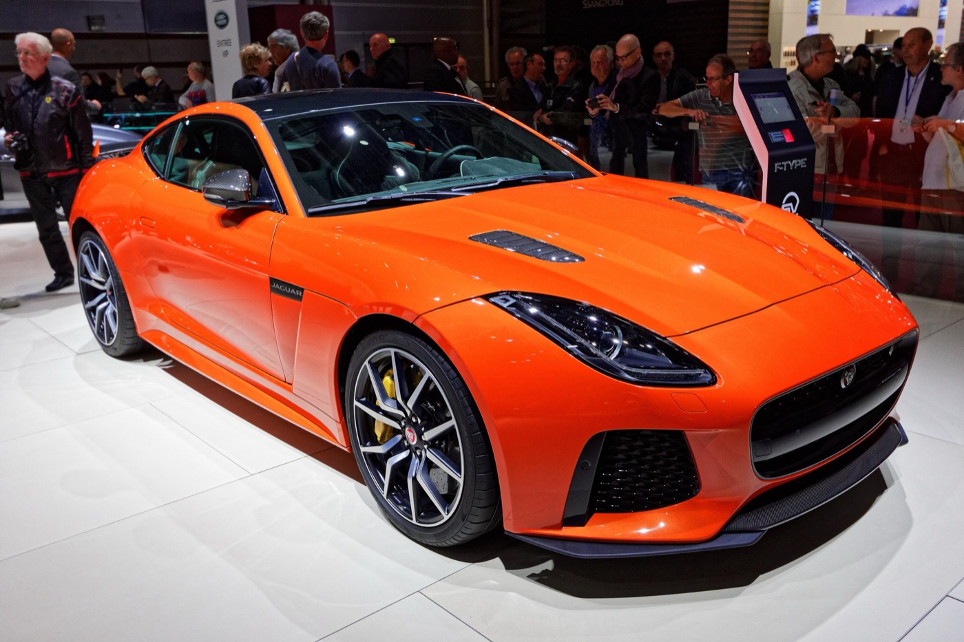 Orange Jaguar F-Type SVR coupe with bonnet vents, black forged wheels and yellow brake calipers on a motor show stand
