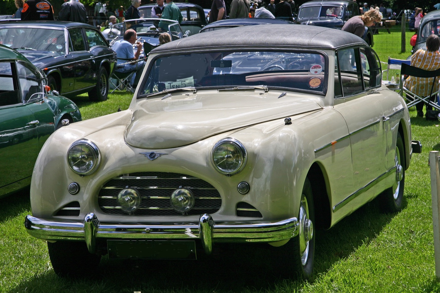 Cream 1954 Jensen Interceptor cabriolet with its hood up, on grass at a car show