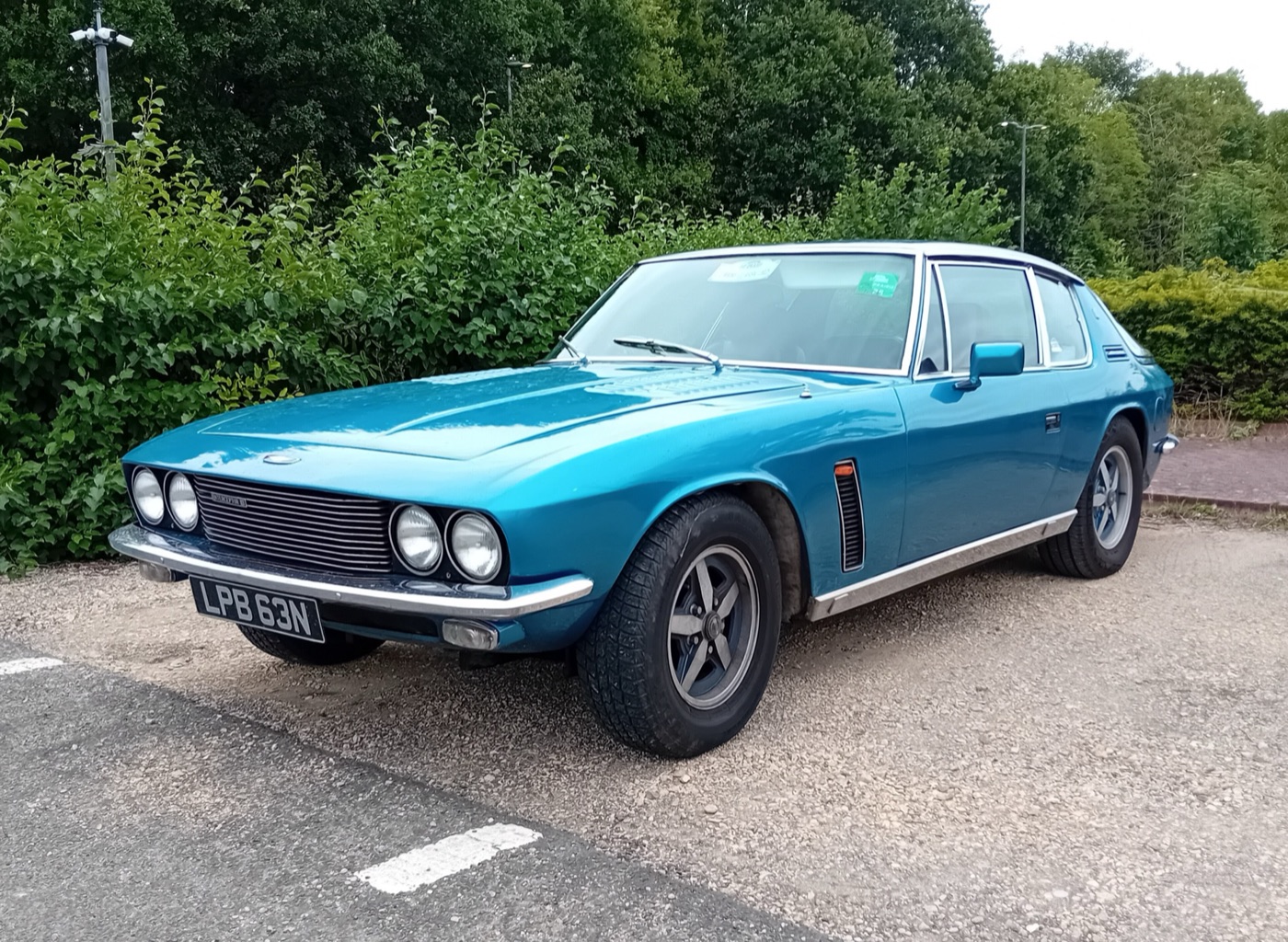 Blue 1974 Jensen Interceptor Mark III registered LPB 63N, front three-quarter view, parked on gravel in front of hedges