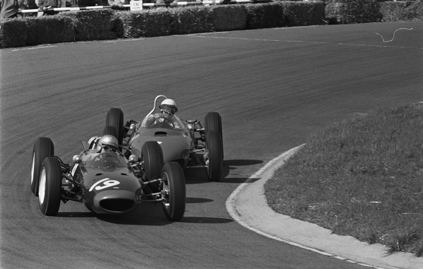 Black and white photograph of John Surtees in the Lola Mk4, number 19, leading Phil Hill’s Ferrari through a corner at Zandvoort