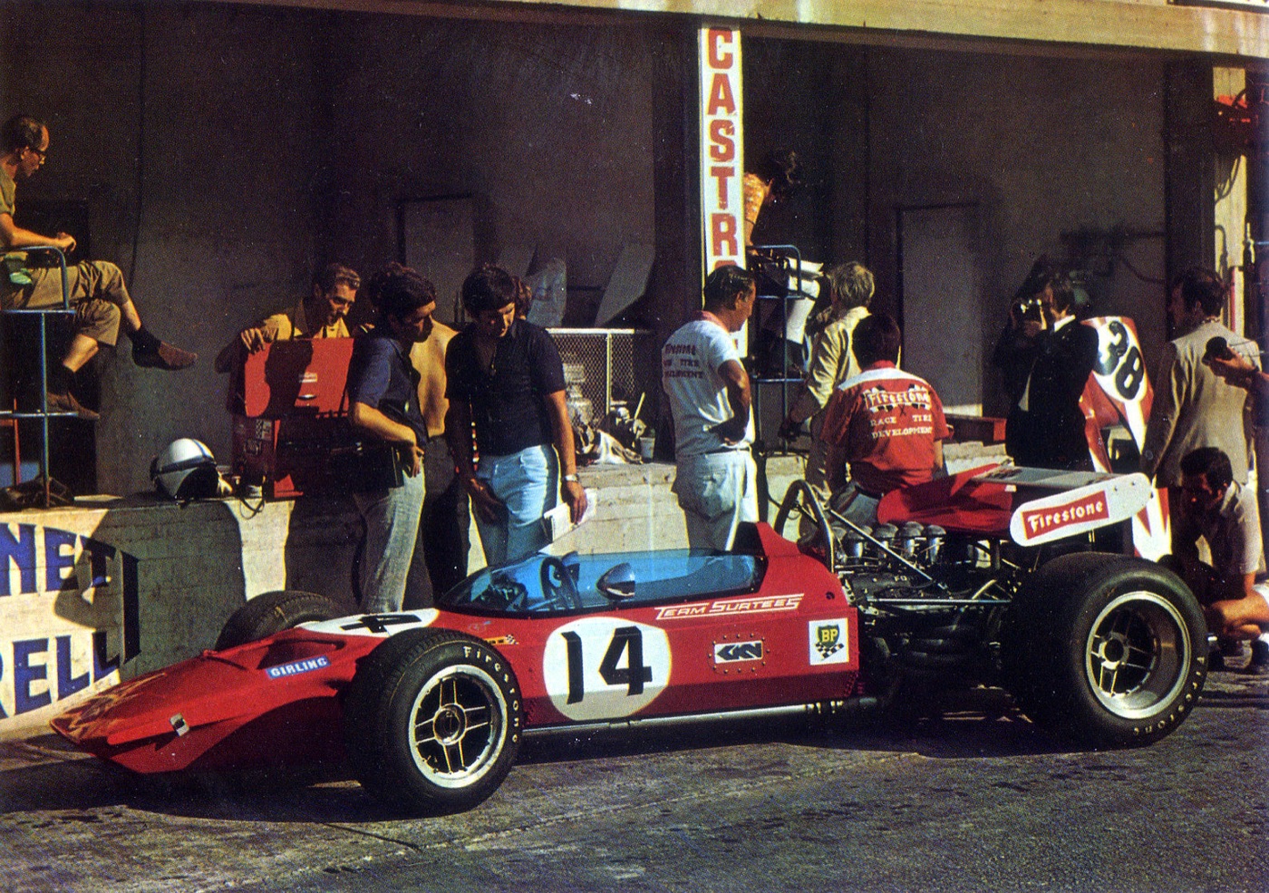 Red Team Surtees TS7 Formula One car, number 14, in the Monza pit lane with mechanics and photographers behind it