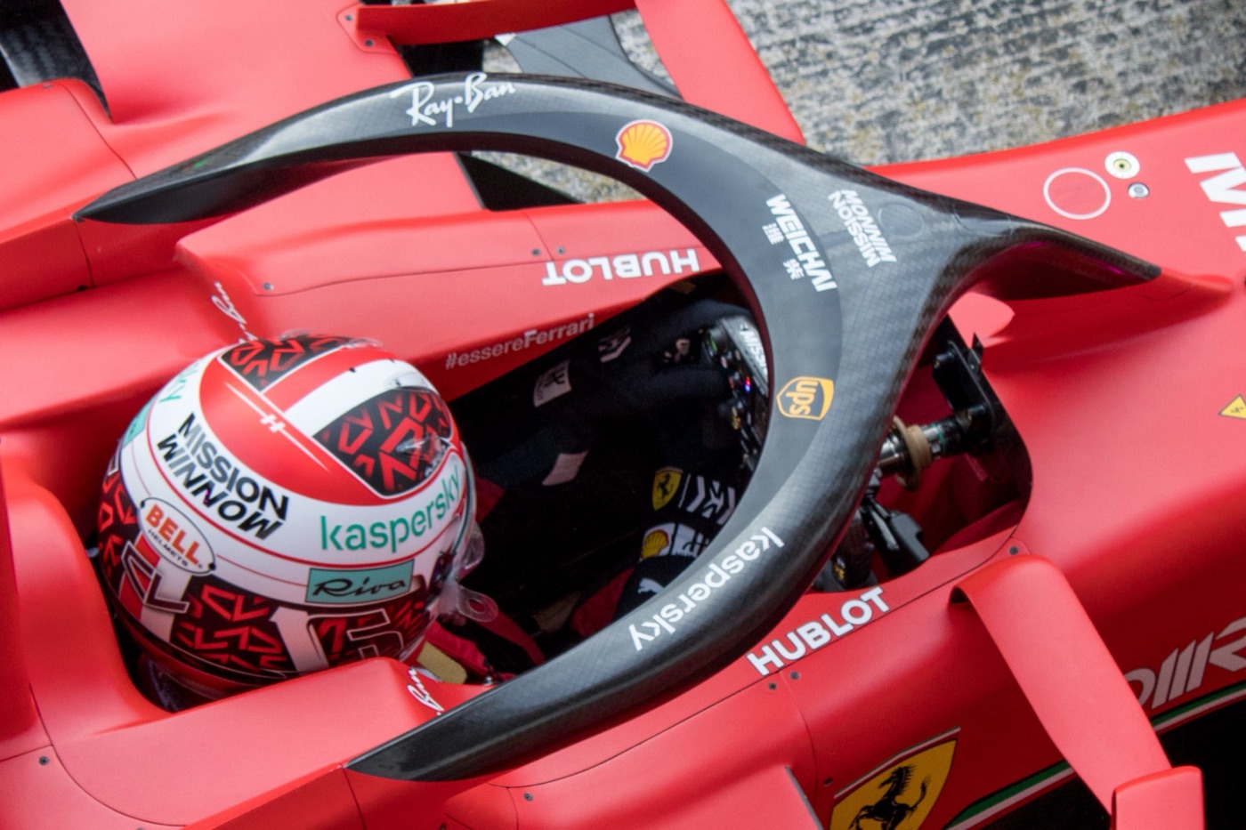 Carbon fibre halo arching over the cockpit of a red Ferrari, with Charles Leclerc in his helmet below it