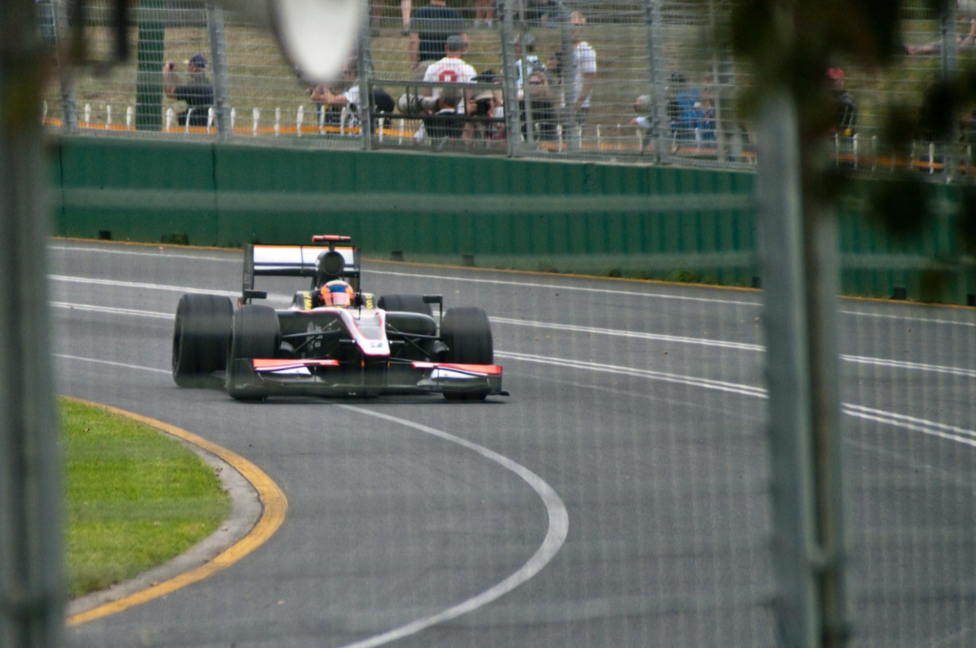 Black, white and red HRT F110 Formula One car, driven by Karun Chandhok in an orange and blue helmet, rounding a corner at Albert Park