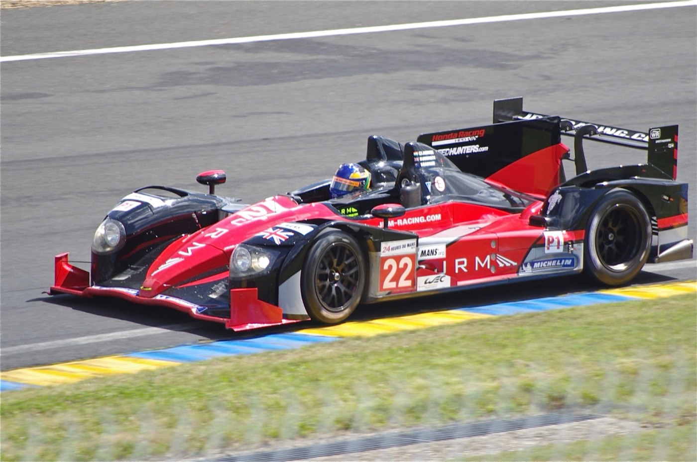 Red and black JRM HPD ARX-03a prototype, number 22, with a Union flag on its nose, on the kerbs at Le Mans