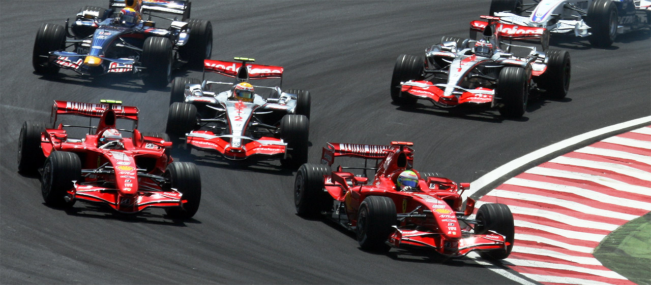 Two red Ferraris and two silver and red McLarens side by side at the start of a race, a Red Bull behind