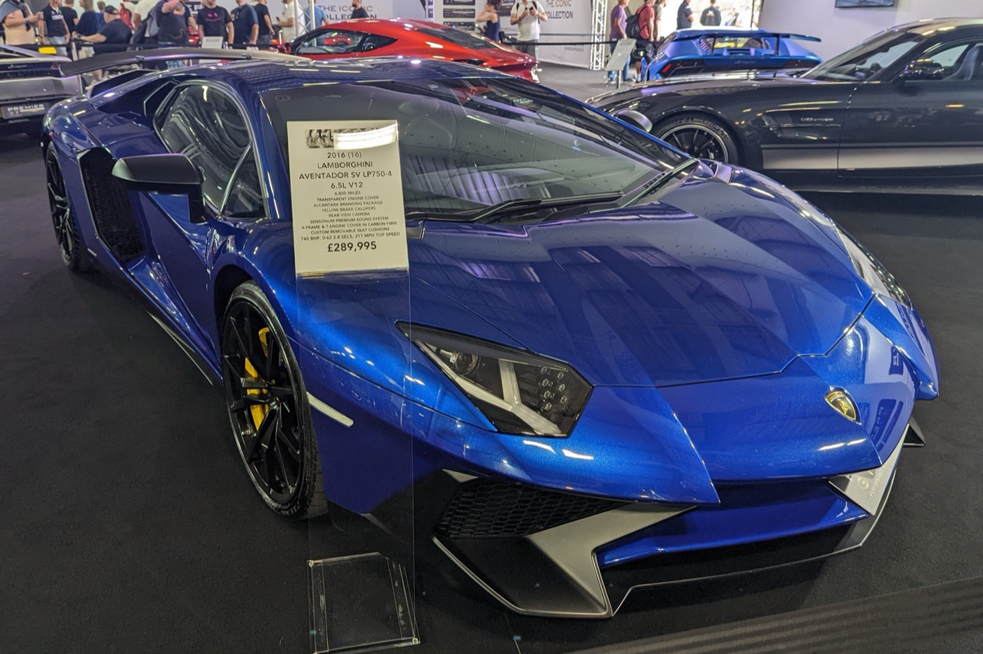 Blue Lamborghini Aventador SV LP750-4 at a show with a price board reading 2016, 4,800 miles, £289,995