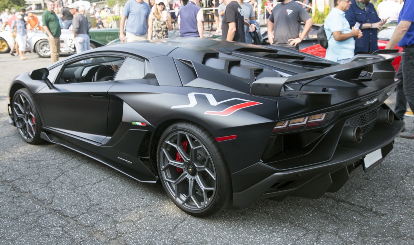 Matt black Lamborghini Aventador SVJ seen from the rear three-quarter, showing its large rear wing, high exhausts and SVJ side graphic