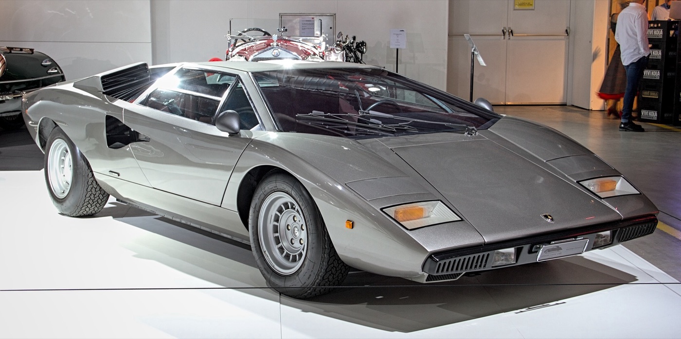 Silver 1976 Lamborghini Countach LP 400 with the roof periscope and slatted air intakes, displayed at a motor show