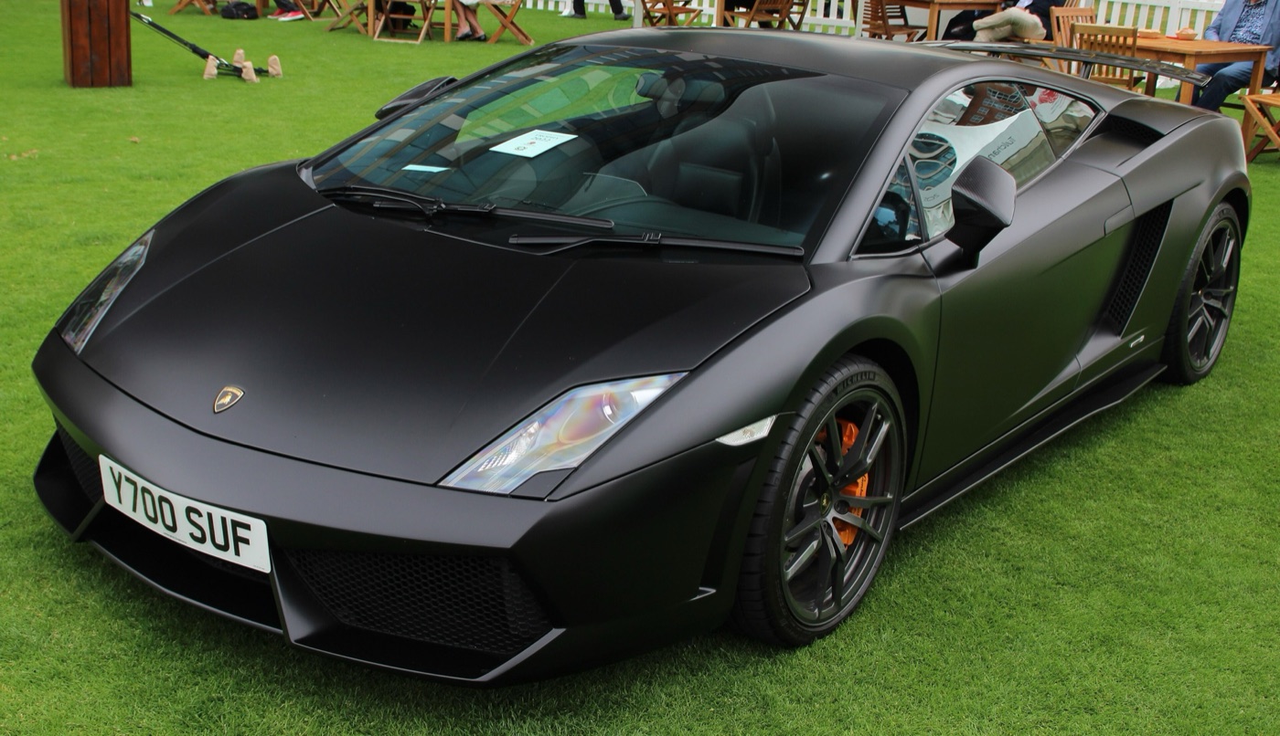 Matt black Lamborghini Gallardo LP550-2 coupé with orange brake calipers, parked on a lawn